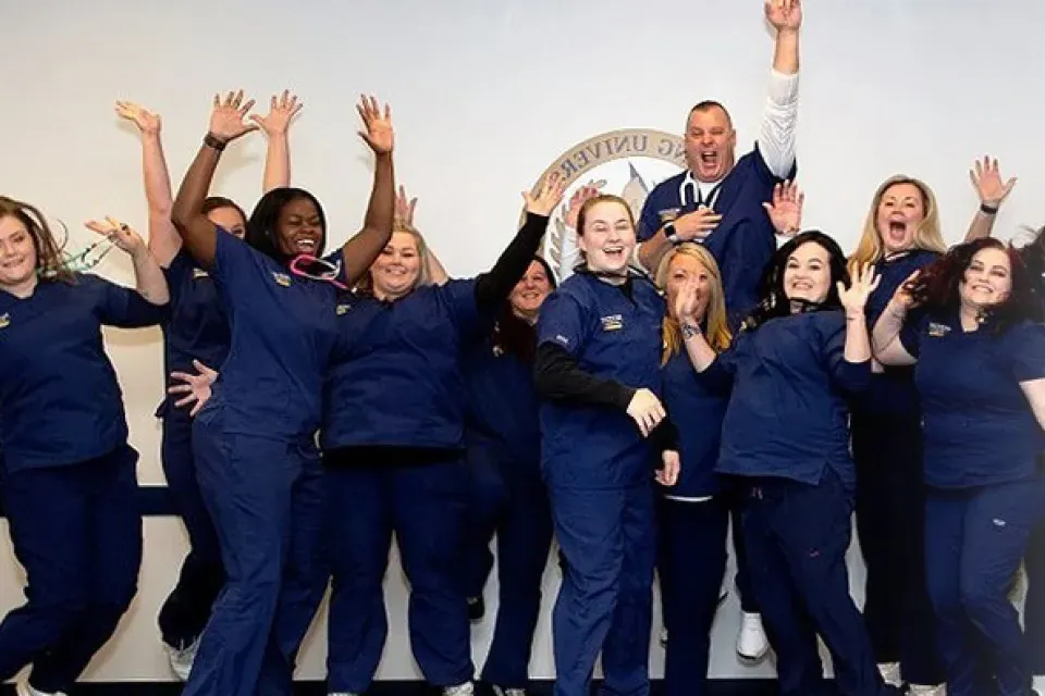 Online BSN nursing school students in scrubs celebrating