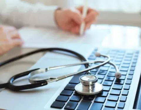 HIM Student Taking Notes in Front of Laptop with Stethoscope